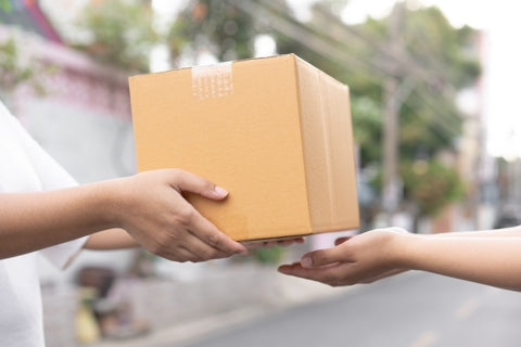 Person handing a cardboard box with GraphXOff product to another person outdoors